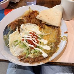 Blue corn chicken breakfast enchiladas with Christmas (red/green), beans, over easy eggs, homemade potatoes with carne and cheese on top.
