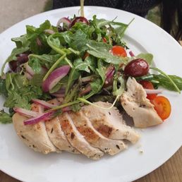 a white plate with a salad and chicken a white plate with a salad and chicken