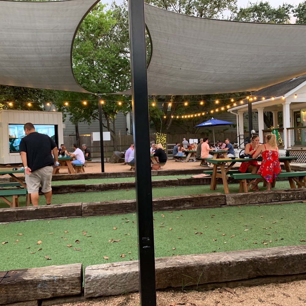 NettBar - a group of people sitting at picnic tables - Cocktail Bars Near Me - Houston, Texas