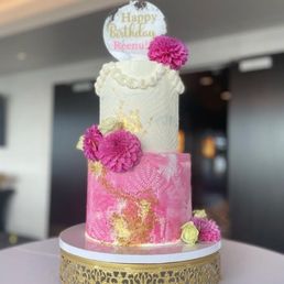 a pink and gold cake with a happy birthday sign on top