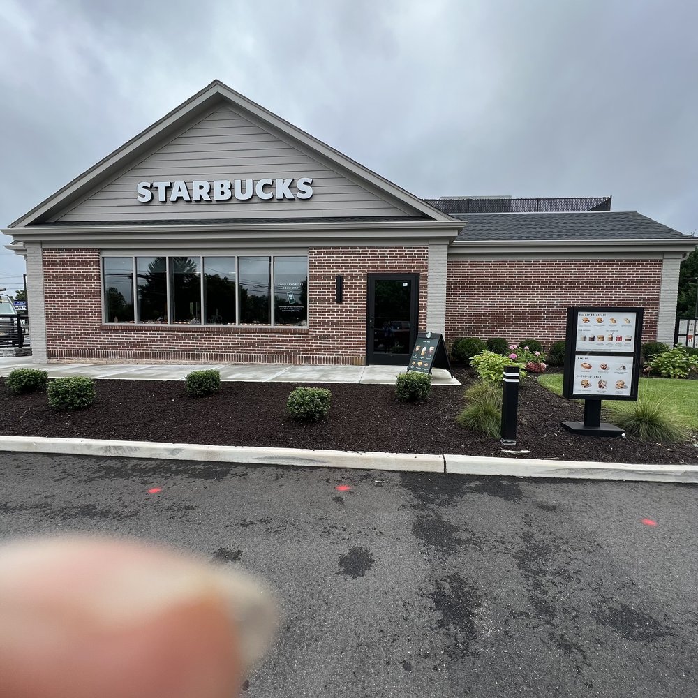 Starbucks - a hand holding up a sign in front of a starbucks - Coffee & Tea Near Me - Smithtown, New York Starbucks - a hand holding up a sign in front of a starbucks - Coffee & Tea Near Me - Smithtown, New York