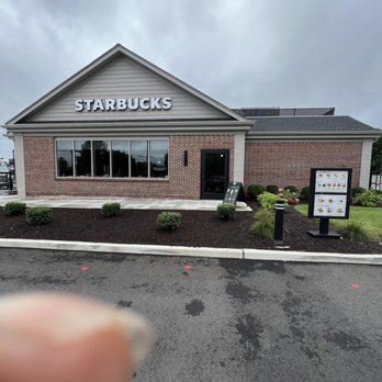 Starbucks - a hand holding up a sign in front of a starbucks - Coffee & Tea Near Me - Smithtown, New York
