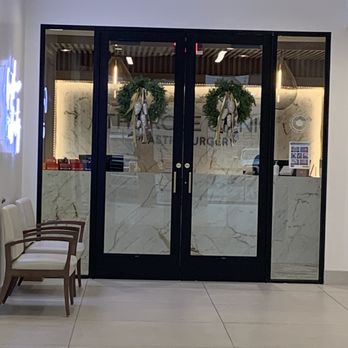 The Rose Clinic - Plastic Surgery in Utah - Double glass doors with black frames and gold handles, decorated with holiday wreaths, lead into a business reception area. - Cosmetic Surgeons Near Me - Orem, Utah