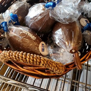 Lazar's Chocolate - A wicker basket filled with chocolate eggs wrapped in clear plastic and sealed with blue clips, placed on a metal cart. - Candy Stores Near Me - Greenvale, New York