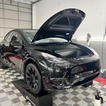 Chicago Ceramic Garrage - Full Frontal PPF - A black Tesla vehicle is parked inside a garage with its front trunk open, surrounded by detailing equipment and cleaning supplies. - Auto Customization Near Me - Chicago, Illinois