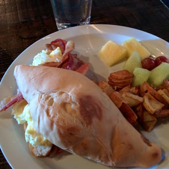 The Yard Cafe - Edible football. Bolillo roll with eggs, bacon, and cheese. Potatoes and fruit on the side. - Tacos Near Me - Seattle, Washington