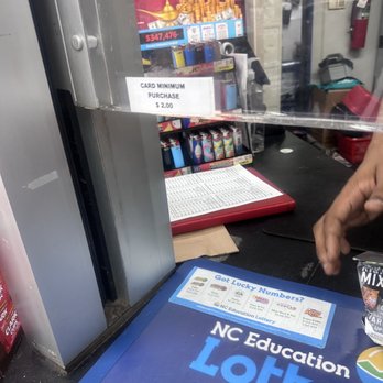 76 - a person holding a can of milk in front of a sign that says nc education lottery - Gas Stations Near Me - Durham, North Carolina