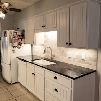 CMW Remodel - a kitchen with white cabinets and black countertops - Flooring Near Me