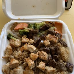 a takeout container of chicken, broccoli, carrots, and rice