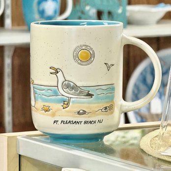 The Sand House - Cream mug with a seagull on the beach and Pt. Pleasant Beach NJ, on a glass counter - Home Decor Near Me - Point Pleasant Beach, New Jersey The Sand House - Cream mug with a seagull on the beach and Pt. Pleasant Beach NJ, on a glass counter - Home Decor Near Me - Point Pleasant Beach, New Jersey
