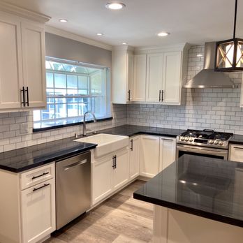 Custom Cuts Construction - a kitchen with white cabinets and black countertops - General Contractors Near Me - Tracy, California