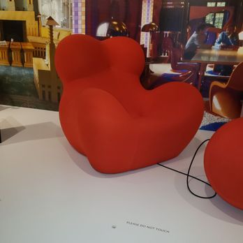 Newfields - An orange, sculptural chair with a rounded, abstract form is placed on a white platform in a museum or exhibit setting. - Parks Near Me - Indianapolis, Indiana