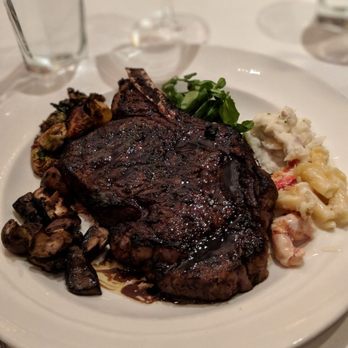 The Capital Grille - The Porcini Rubbed Bone-In Ribeye, with some sides scooped around it. - Steakhouses Near Me - Mclean, Virginia The Capital Grille - The Porcini Rubbed Bone-In Ribeye, with some sides scooped around it. - Steakhouses Near Me - Mclean, Virginia