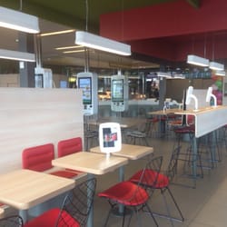 McDonald's - Salle principale avec des iPads sur des tables et d'énormes écrans de commande.