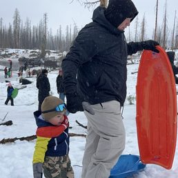 Playing in the snow, snowboarding, father and son, mom and daughter in the background