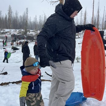 Tamarack Sno-Park - Playing in the snow, snowboarding, father and son, mom and daughter in the background - Sledding Near Me - Shaver Lake, California