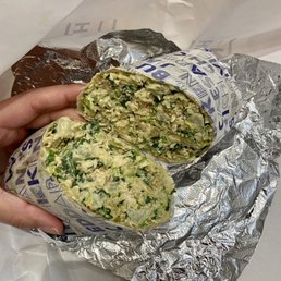 a person holding a sandwich wrapped in foil a person holding a sandwich wrapped in foil