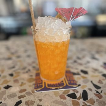 Happy Medium - a glass of orange juice with a straw and umbrella - Cocktail Bars Near Me - San Diego, California
