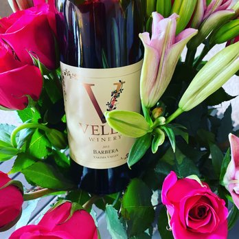 Velen Winery - a bottle of red wine surrounded by pink roses - Wineries Near Me - Zillah, Washington Velen Winery - a bottle of red wine surrounded by pink roses - Wineries Near Me - Zillah, Washington