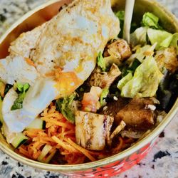 Chimac - KBBQ Jerk Chicken Bowl and white rice, topped with carrots, cucumbers,, cabbage, lettuce, and egg.