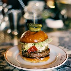 Coucou - Burger Americaine | pastured wagyu beef, caramelized onion, cognac everything sauce, frisee, red pepper, toasted brioche - $27