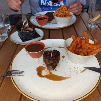 THE ASH - 250 g Ribeye steak with curly fries, BBQ sauce and Portobello mshrooms. 180 g Tenderloin steak with sweet potatoes fries and pepper sauce. - Steakhouses Near Me - Essen, NW THE ASH - 250 g Ribeye steak with curly fries, BBQ sauce and Portobello mshrooms. 180 g Tenderloin steak with sweet potatoes fries and pepper sauce. - Steakhouses Near Me - Essen, NW