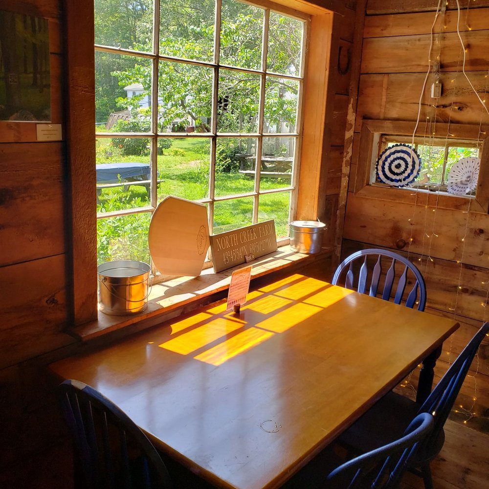 Kristy's Cafe - a wooden table and chairs in front of a window - Cafes Near Me - Phippsburg, Maine