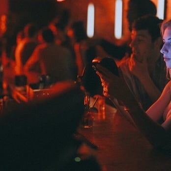 Mme Lee - a woman sitting at a bar looking at her cell phone - Lounges Near Me - Montreal, Quebec Mme Lee - a woman sitting at a bar looking at her cell phone - Lounges Near Me - Montreal, Quebec
