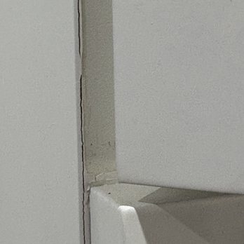 Rainier Woodworking Company - paint cracking.  It appears they spray paint while doors are attached.  This is excess paint that got stuck between door hinge side opening. - Cabinetry Near Me - Tacoma, Washington
