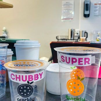 Quickly - Two transparent plastic cups with colorful labels reading 'CHUBBY' and 'SUPER' are on a counter, featuring fruit illustrations and the 'quickly' brand. - Bubble Tea Near Me - Johnstown, Colorado