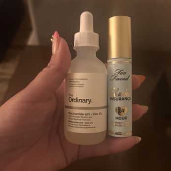 SEPHORA - A person holds two skincare and makeup products, The Ordinary Niacinamide serum and Too Faced Shadow Insurance primer, in a room with a blurred background. - Cosmetics & Beauty Supply Near Me - Brooklyn, New York