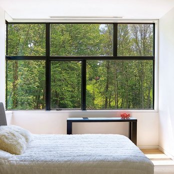 Builders FirstSource - Large black-framed picture windows fill a bright bedroom with natural light, offering a wide view of green trees outside. - Building Supplies Near Me - Idaho Falls, Idaho Builders FirstSource - Large black-framed picture windows fill a bright bedroom with natural light, offering a wide view of green trees outside. - Building Supplies Near Me - Idaho Falls, Idaho