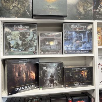 Cool Stuff - Souls games physical games! - A retail shelf features board games like Elden Ring and Bloodborne, with multiple editions and expansions, in a store specializing in gaming products. - Comic Books Near Me - Virginia Beach, Virginia
