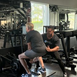 Elite Fitness - Fabian coaching a client through a squat at Elite Fitness.