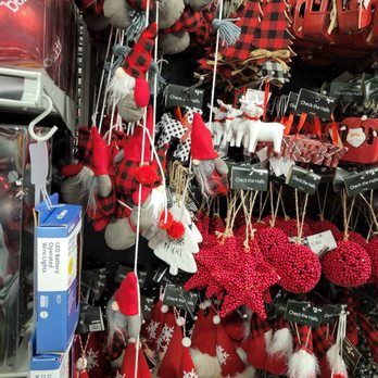 At Home - Gnome and cabin feel ornaments. - Display of Christmas ornaments such as gnome, Santa, reindeer, and pinecone decorations in red, gray, and plaid patterns, hanging on a store pegboard. - Home Decor Near Me - Albuquerque, New Mexico