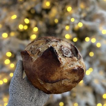 Breaking Bread 803 - a hand holding a loaf of bread in front of a christmas tree - Bakeries Near Me - Columbia, South Carolina Breaking Bread 803 - a hand holding a loaf of bread in front of a christmas tree - Bakeries Near Me - Columbia, South Carolina