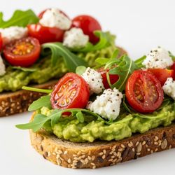Multigrain toast topped with seasoned avocado, roasted tomato, arugula, and goat cheese