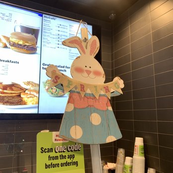McDonald's - Cute Seasonal Decor - A bunny-themed decoration with a 'Happy Easter' banner is displayed inside a McDonald's, near a digital menu screen and paper cups. - Fast Food Near Me - Naperville, Illinois