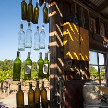 Tudal Winery - a variety of wine bottles hanging from a pergolated roof - Wineries Near Me - Saint Helena, California Tudal Winery - a variety of wine bottles hanging from a pergolated roof - Wineries Near Me - Saint Helena, California