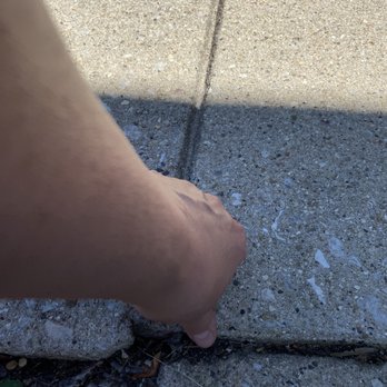 Perma-Seal Basement Systems - a person's hand reaching for a crack in the sidewalk - General Contractors Near Me - Burr Ridge, Illinois Perma-Seal Basement Systems - a person's hand reaching for a crack in the sidewalk - General Contractors Near Me - Burr Ridge, Illinois
