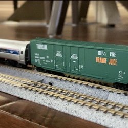The Train Crossing - A Kato ACS-64 engine on the track 1 with an Amtrak amfleet passenger car with a tropical orange juice transport car attached to it.