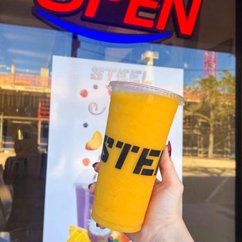 STEEL - a hand holding a drink in front of an open sign - Juice Bars & Smoothies Near Me - Sarasota, Florida STEEL - a hand holding a drink in front of an open sign - Juice Bars & Smoothies Near Me - Sarasota, Florida
