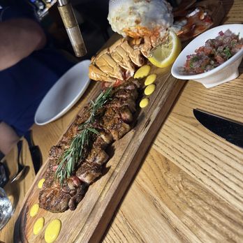 Platea - A wooden serving board holds grilled meat, seafood, lemon, and sauces, with a small bowl of chopped seafood and a scoop of ice cream on top. - Peruvian Near Me - Pinecrest, Florida