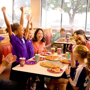 Chuck E. Cheese - a group of people sitting at a table in a fast food restaurant - Pizza Near Me - Fort Wayne, Indiana