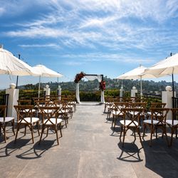 Hollywood Hills outdoor wedding ceremony setup with crossback chairs, market umbrellas, and panoramic Los Angeles views.