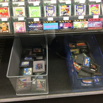 Replay'd - Baskets contain various video game cartridges and handheld consoles, with a shelf above holding boxed video games for different gaming systems. - Electronics Near Me - Allston, Massachusetts