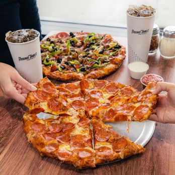 Round Table Pizza - two people holding slices of pizza - Pizza Near Me - Simi Valley, California Round Table Pizza - two people holding slices of pizza - Pizza Near Me - Simi Valley, California