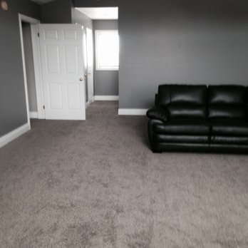 Floors In Motion - a living room with a black leather couch - Flooring Near Me Floors In Motion - a living room with a black leather couch - Flooring Near Me