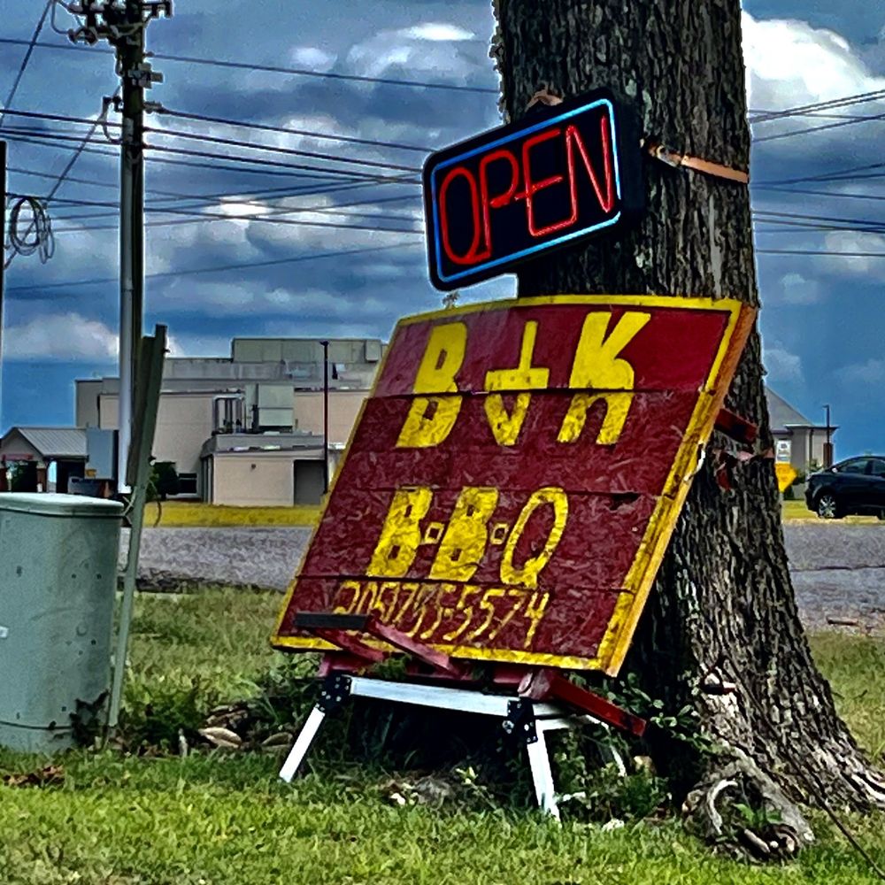 an open sign next to a tree an open sign next to a tree