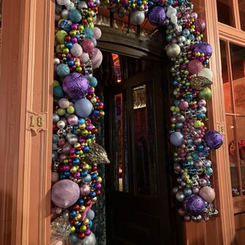Papi - A door is framed by a large, colorful Christmas ornament wreath with various baubles and decorations. - Cocktail Bars Near Me - Portland, Maine